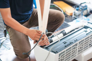 Technicien en train d’entretenir une unité de climatisation, nettoyage et contrôle du circuit