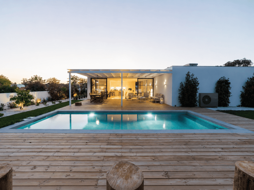 Unité extérieure de pompe à chaleur air-eau installée contre la façade d’une villa moderne avec piscine